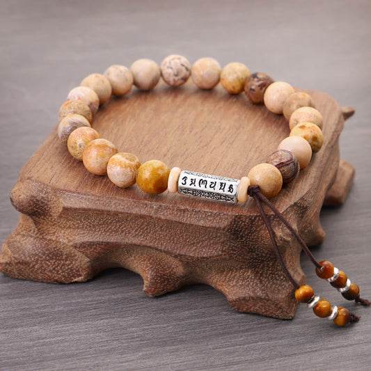 Weathered Stone Om Mani Padme Hum Bracelet – stone beads with Tibetan mantra cylinder on wooden display, meditation bracelet