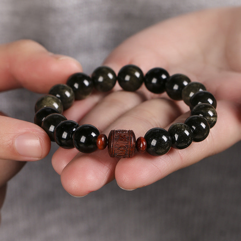 Gold Sheen & Rainbow Obsidian Fu Bracelet – held in palm showing carved center bead, mens bracelet