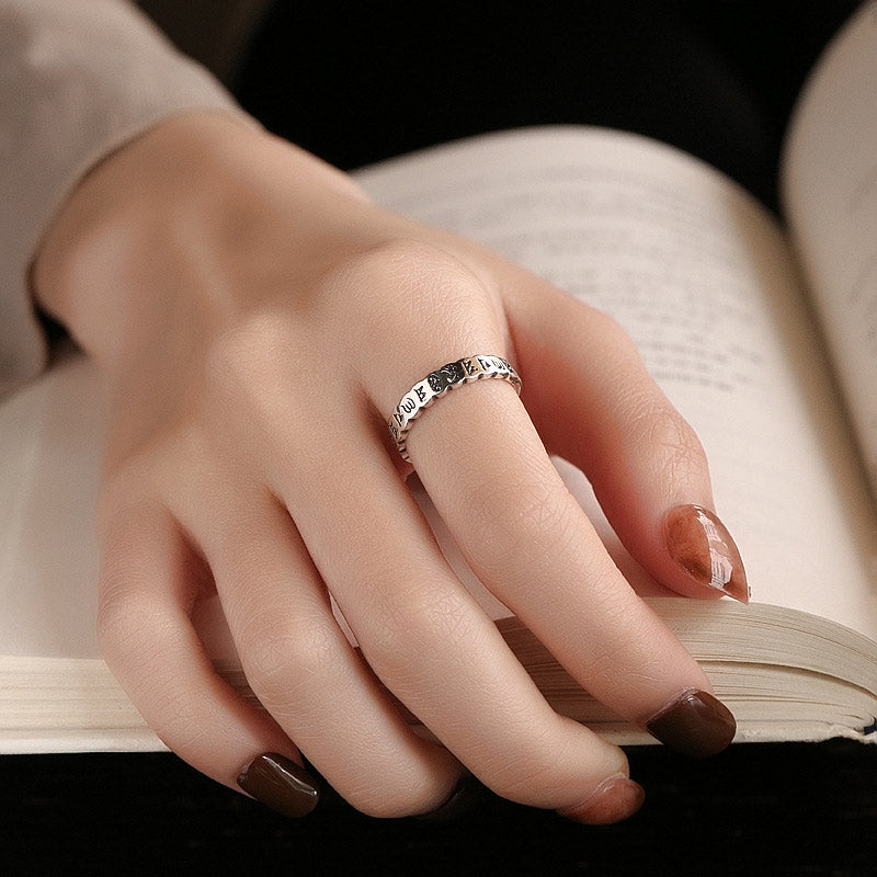 925 Sterling Silver Om Mani Padme Hum Ring – silver mantra ring worn on finger resting on open book, lifestyle jewelry