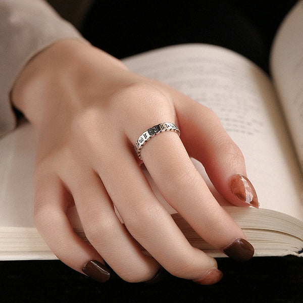 925 Sterling Silver Om Mani Padme Hum Ring – silver mantra ring worn on finger resting on open book, lifestyle jewelry