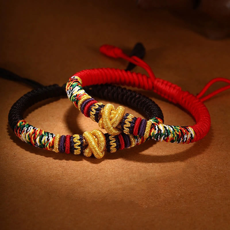Tibetan Mantra Bracelet – Black cord bracelet with gold knots and multicolor accents on brown surface, pair