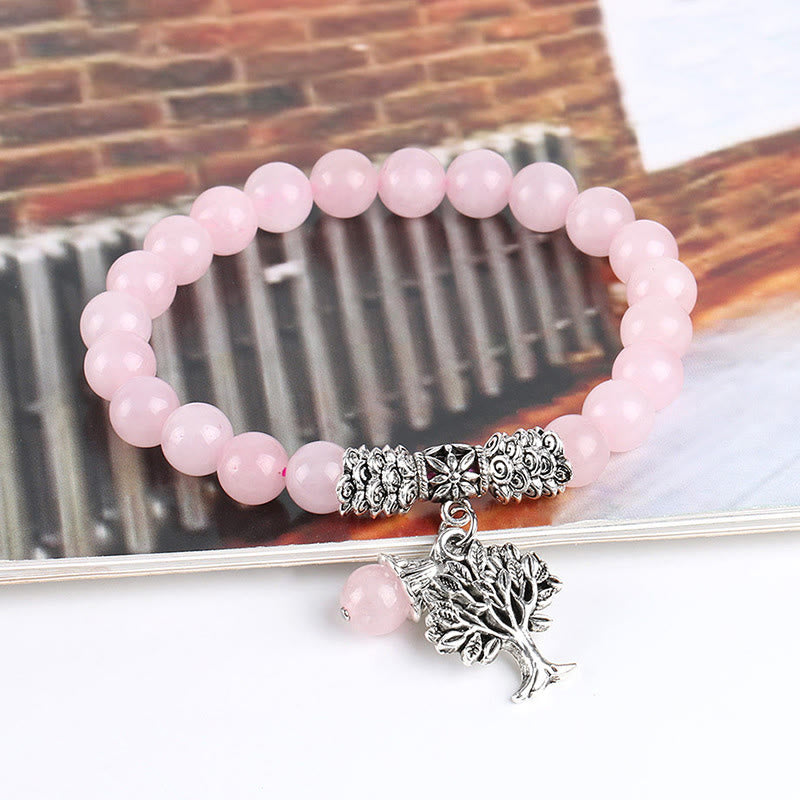 Tree of Life rose quartz bracelet with translucent pink beads, antique silver tree charm showing branches and roots, silver floral barrel spacer.