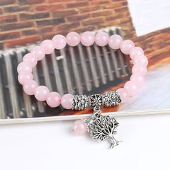 Tree of Life rose quartz bracelet with translucent pink beads, antique silver tree charm showing branches and roots, silver floral barrel spacer.