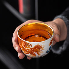 Dragon Phoenix Crane Gilt Ceramic Teacup – gold interior with traditional sun and flame motif, overhead top-down view, handcrafted