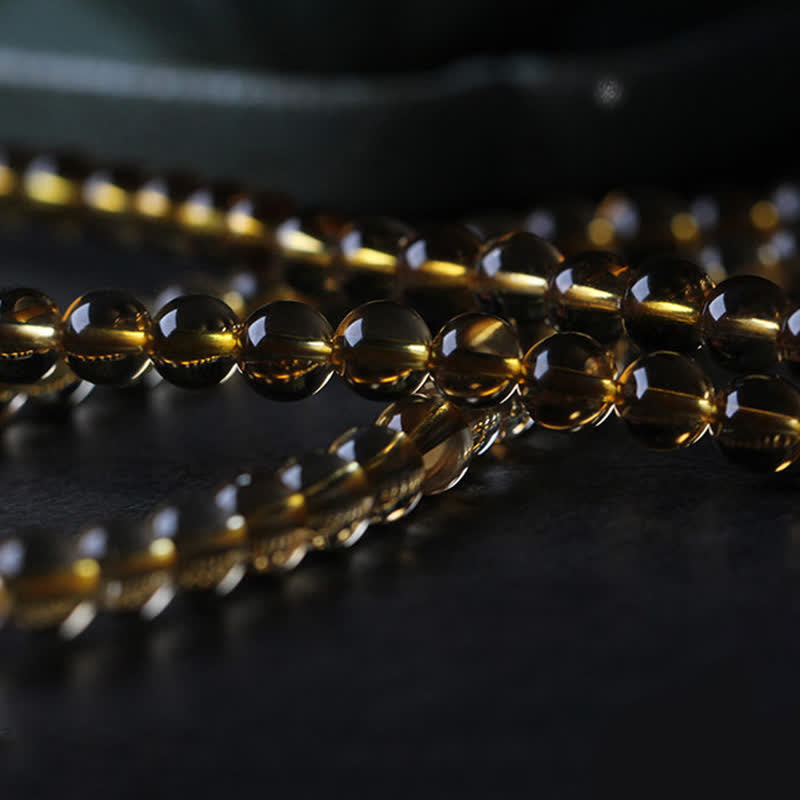 Citrine Mala Bracelet – Close-up of polished golden citrine beads strand on reflective surface