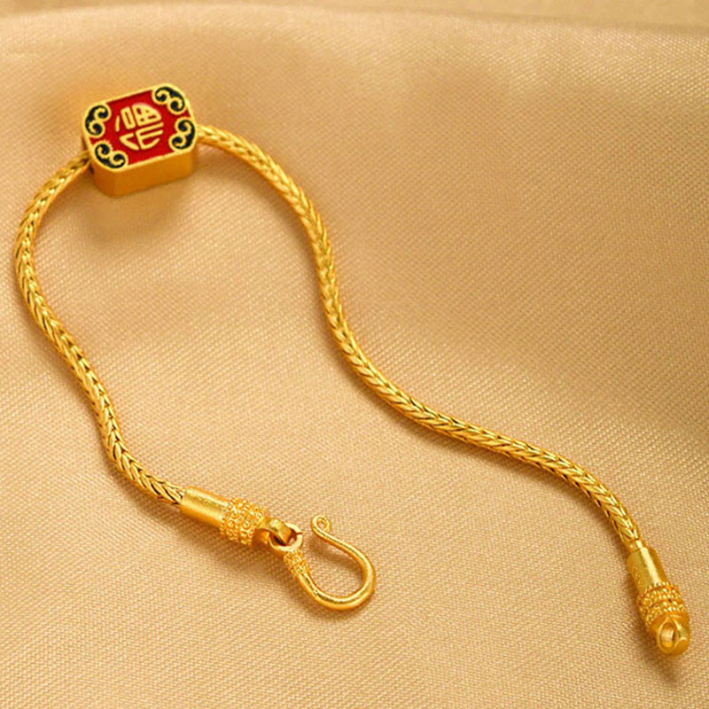18K Gold Om Mani Padme Hum Koi Fish Bracelet – red Fu character square charm on gold chain, beige fabric, diagonal top-down view