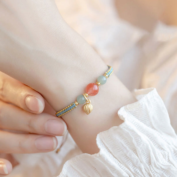 Red Agate Jade Lotus Bracelet – blue-gray gold cord with pink and jade beads, shell charm, white ruffled sleeve lifestyle close-up