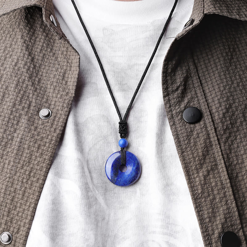Lucky Coin Pendant Healing Crystal Gemstone Necklace – Clear rock crystal quartz donut pendant on black braided cord, white background