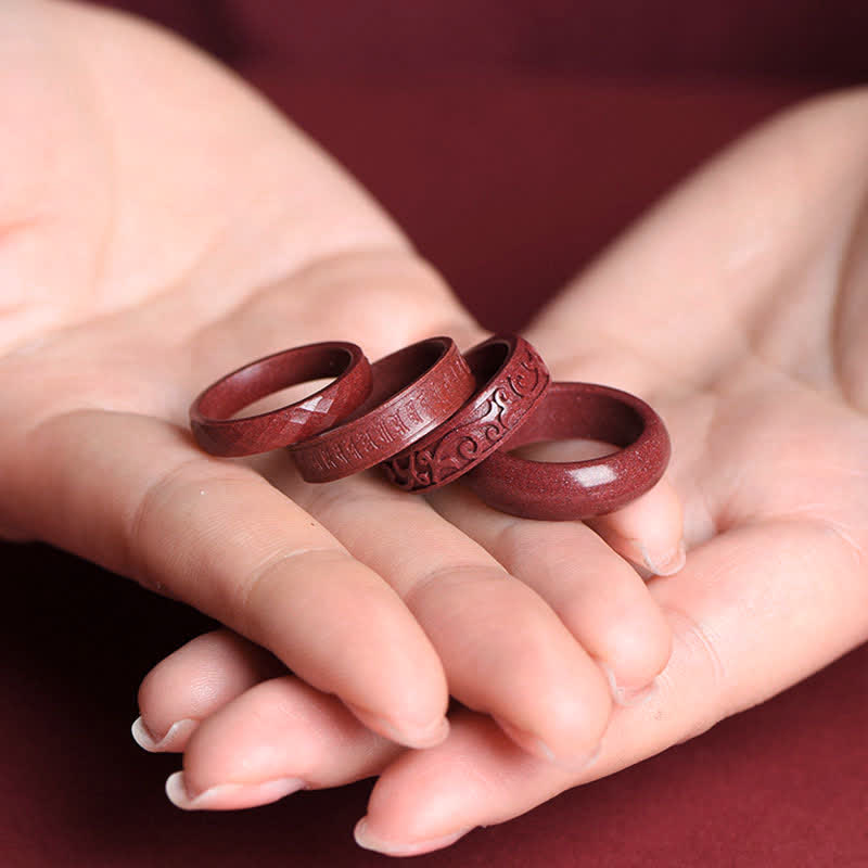 Cinnabar Om Mani Padme Hum Blessing Ring – four cinnabar rings in open palm, faceted carved and plain styles, French manicure hands