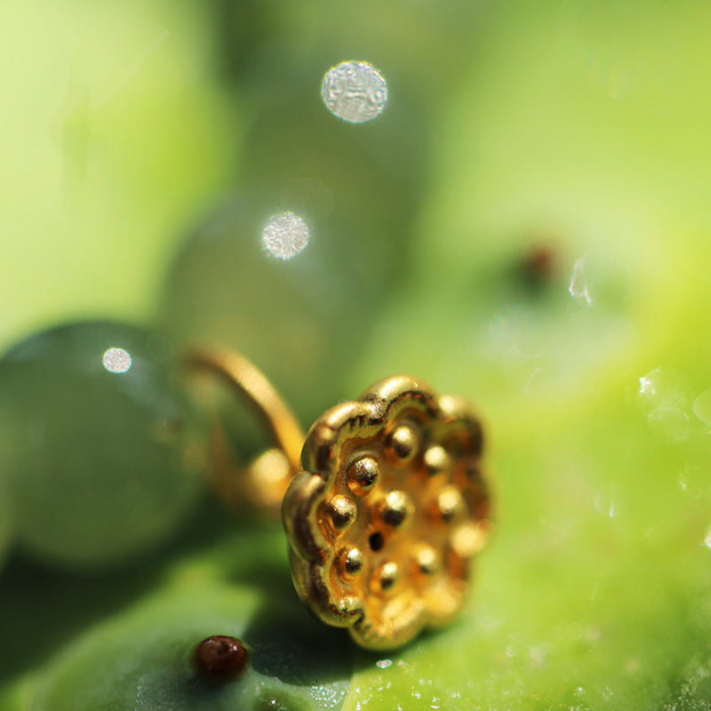 Jade Lotus Abundance Bracelet – Gold lotus pod charm on jade beads near finger, warm bokeh, lotus bracelet