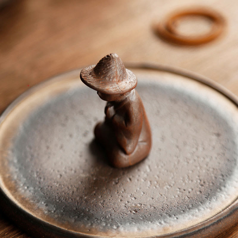 Ceramic meditating figure detail on teapot lid, artisan crafted