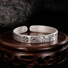 Antique silver Pixiu bracelet on dark carved wooden stand, featuring mythical wealth beast, lucky coin motifs and Buddhist scripture engraving