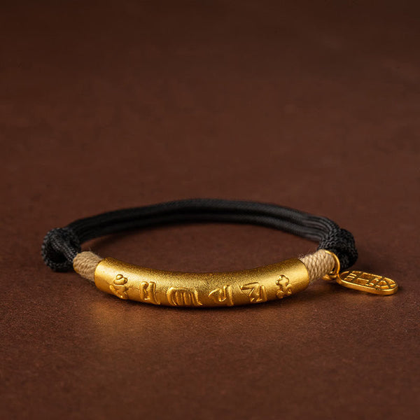 Adjustable black cord bracelet with gold cylindrical bead featuring red enamel Jinbang Timing academic success characters and mountain motifs on brown surface