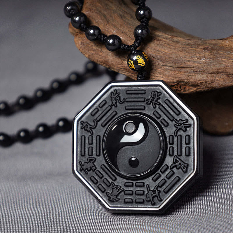 Black Obsidian Yin Yang Pendant Necklace - close-up of yin-yang bagua pendant with carved trigrams on weathered wood, spiritual amulet