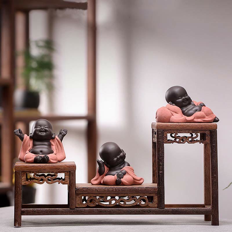 Laughing Buddha Purple Clay Maitreya Statue – low-angle seated figure in sage green robe, matte dark brown skin, wood-grain surface, minimalist zen styling