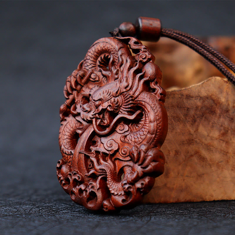 Lightning Jujube Wood Dragon Pendant - 3/4 view on driftwood prop, rich reddish-brown grain, Spiritual