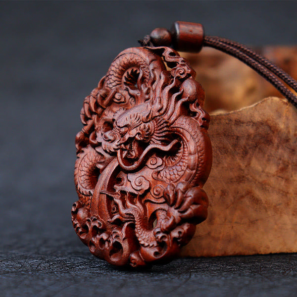 Lightning Jujube Wood Dragon Pendant - 3/4 view on driftwood prop, rich reddish-brown grain, Spiritual