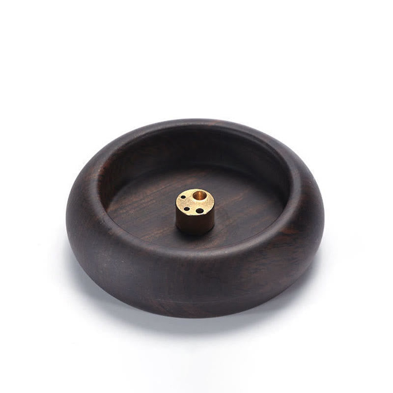 Dark wood incense holder with brass center on white background, healing
