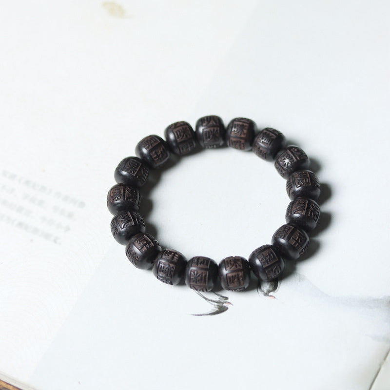 Ebony Wood Mantra Bracelet – Flat lay circle on white with faint book page backdrop, meditation beads