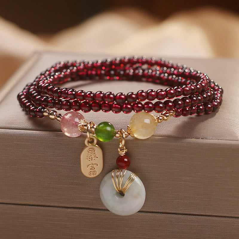 Garnet triple-wrap bracelet with bai fu sudden wealth gold tag and white jade ping an kou peace buckle disc with gold wire wrapping on taupe jewelry box display