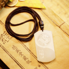White Jade PiXiu Pendant – White jade PiXiu yin-yang pendant with engraved dragon pattern on brown cord