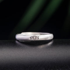 Lotus Enlightenment Ring - engraved lotus band on dark textured surface with green bokeh, silver