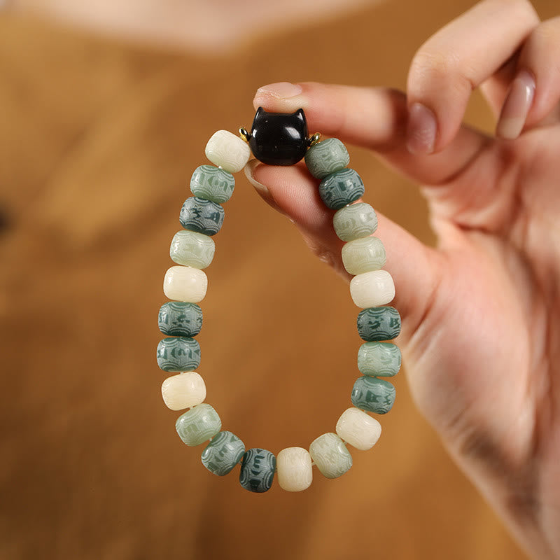 Bodhi Seed Cat Head Bracelet – Green and ivory ombre beads held in hand with glossy black cat charm, natural material bracelet
