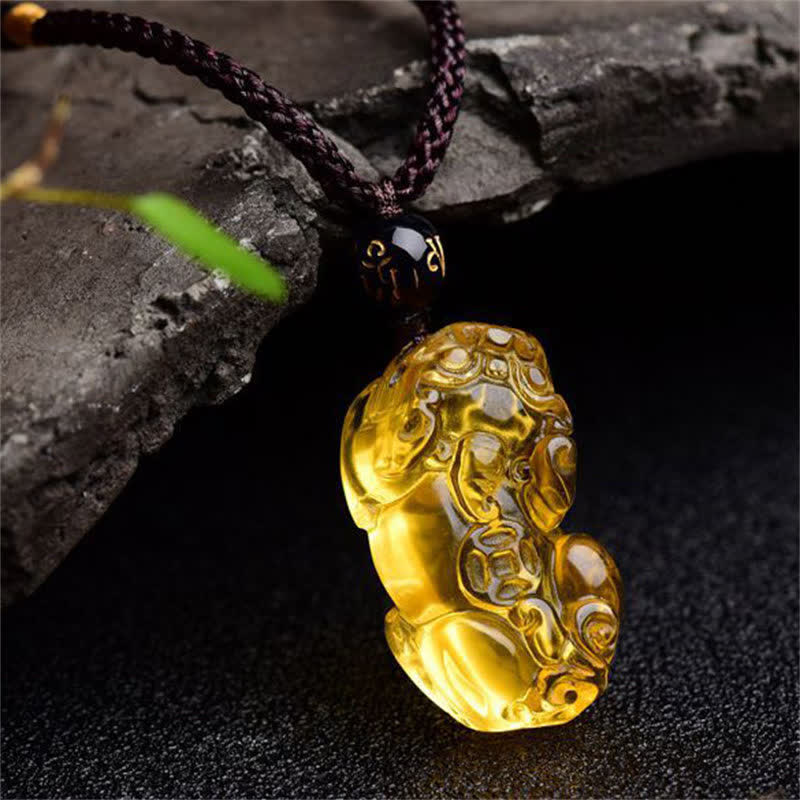 Citrine PiXiu Necklace Pendant – Golden PiXiu pendant on dark stone with green leaf, happiness jewelry