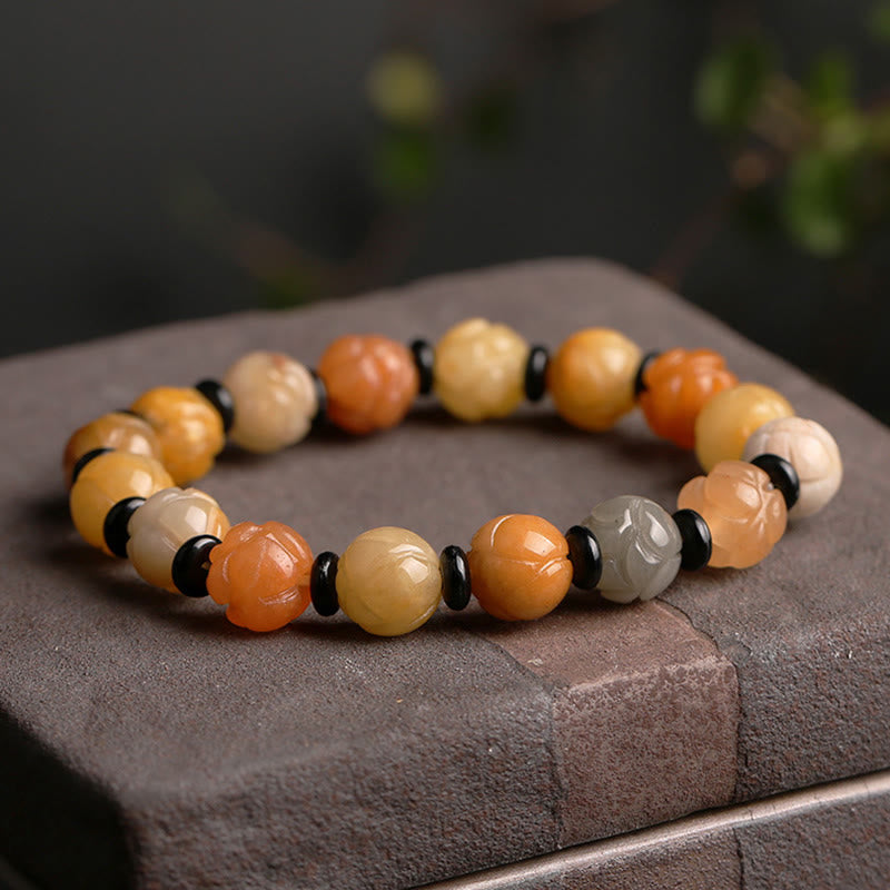 Golden Silk Jade Lotus Bracelet – Amber and cream lotus beads with black spacers on dark stone, protection bracelet