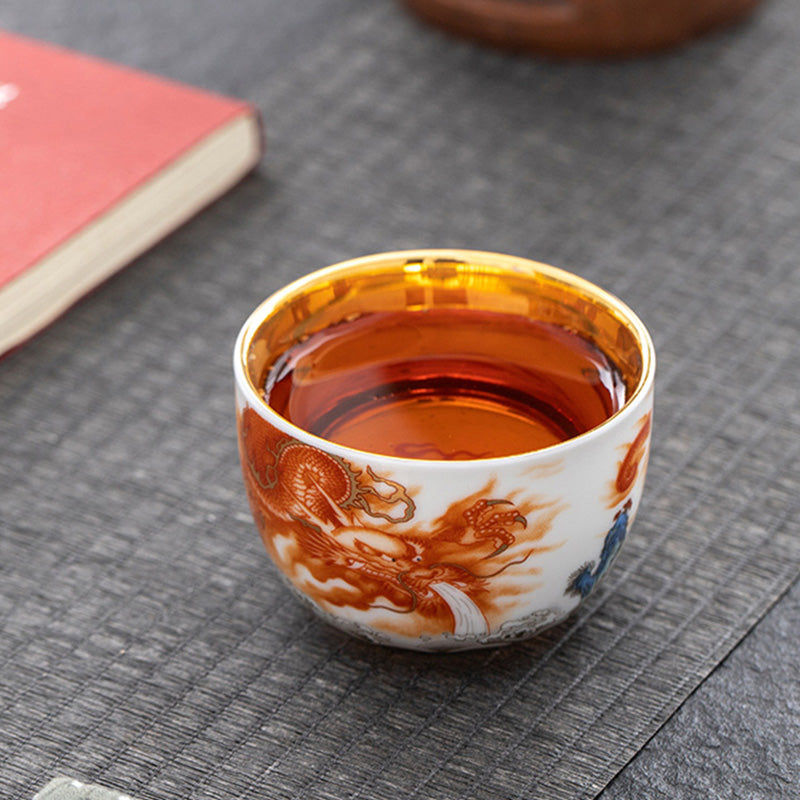 Dragon Phoenix Crane Gilt Ceramic Teacup – tea pouring action with dragon cup and ceramic pitcher, gold-lined interior, lifestyle
