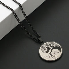 Tree of Life Titanium Steel Necklace – black pendant on dark surface with white block, angled view, connection pendant