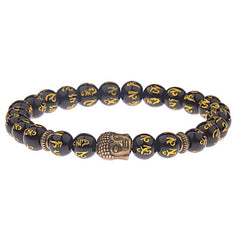 Tibetan Buddha Om Mani Padme Hum Amulet Bracelet - black obsidian beads with gold Tibetan Buddhist mantra, antique bronze Buddha head charm, metal spacer accents, prayer bracelet on dark textured background