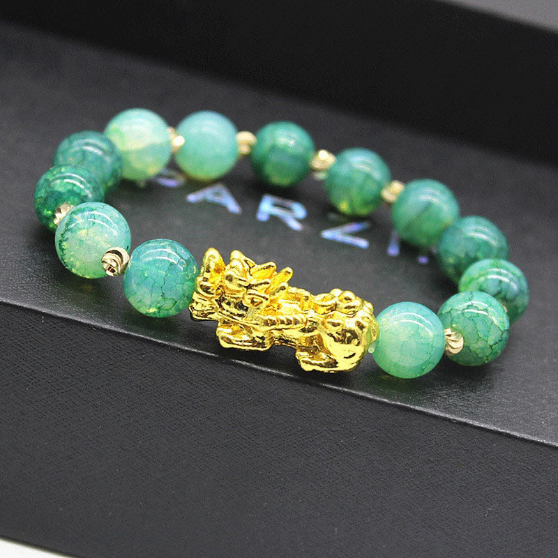 Cyan Jade PiXiu Success Bracelet – close-up of gold PiXiu with textured green jade beads on black surface, wealth luck jewelry