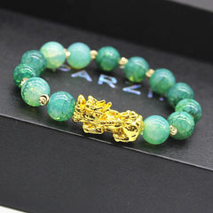 Cyan Jade PiXiu Success Bracelet – close-up of gold PiXiu with textured green jade beads on black surface, wealth luck jewelry