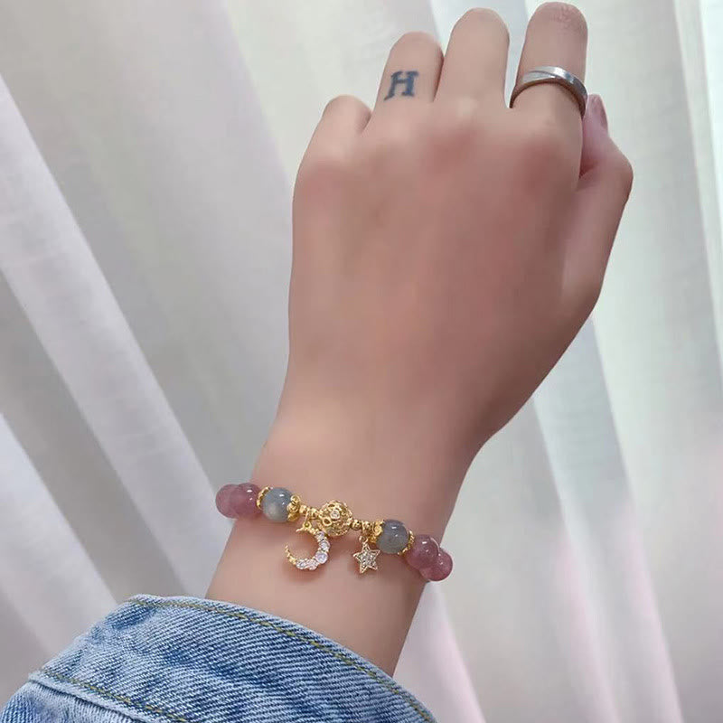 Strawberry Quartz moon star bracelet worn on wrist showing pink and gray-blue beads, gold pavé crystal moon and star charms with denim jacket styling.