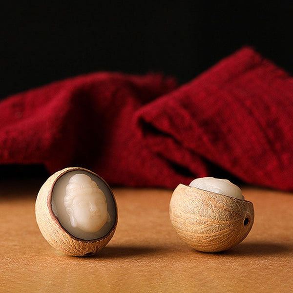 Bodhi Seed Blessing Keychain - two halved bodhi seeds with carved ivory Buddha figures visible inside on crimson fabric, artistry