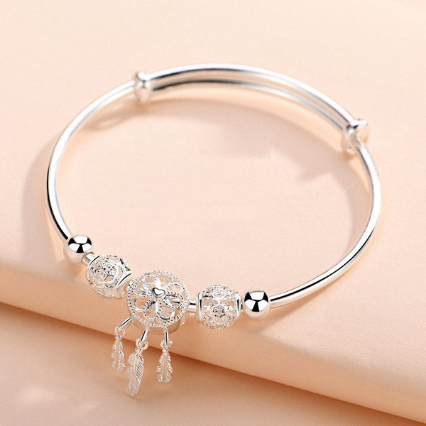 Dream Catcher Blessing Bracelet – Silver bangle on warm peach background showing full charm cluster, product photo