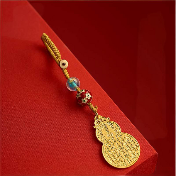 Antique gold gourd keychain with gold cord on red gift box