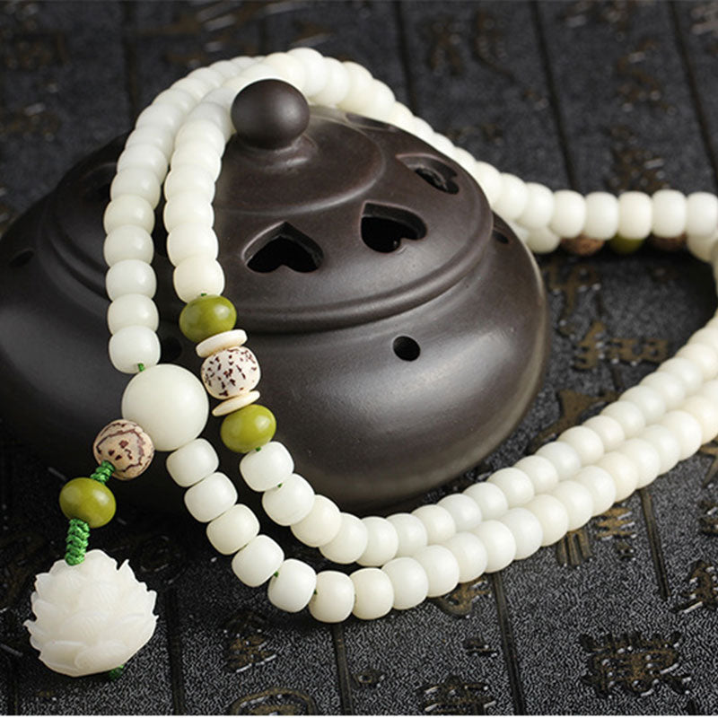 Bodhi Seed Lotus Mala - looped around dark incense burner on calligraphy mat, serene ritual setting