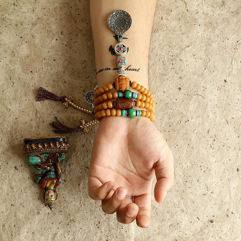108 Bodhi Seed Mala Bracelet – Amber bracelet on forearm with turquoise and tassel pendants