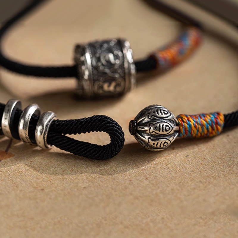Tibetan Om Mani Padme Hum Wrap Bracelet – Silver fish-eye engraved tail bead with red blue yellow woven cord, hand-held detail close-up