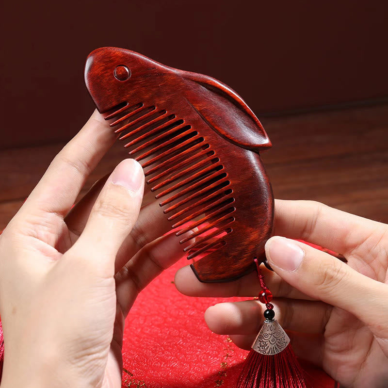 Hands holding cute bunny-shaped red sandalwood massage comb with red tassel