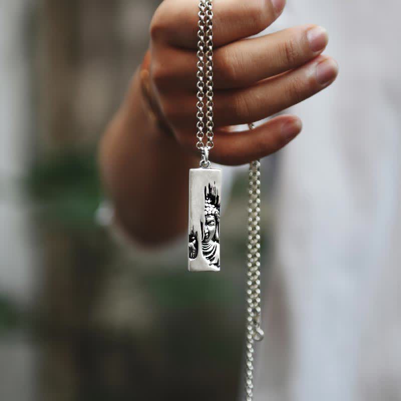 Tathagata Buddha Copper Amulet Necklace – hand dangling Buddha pendant by silver chain with outdoor bokeh, closeup