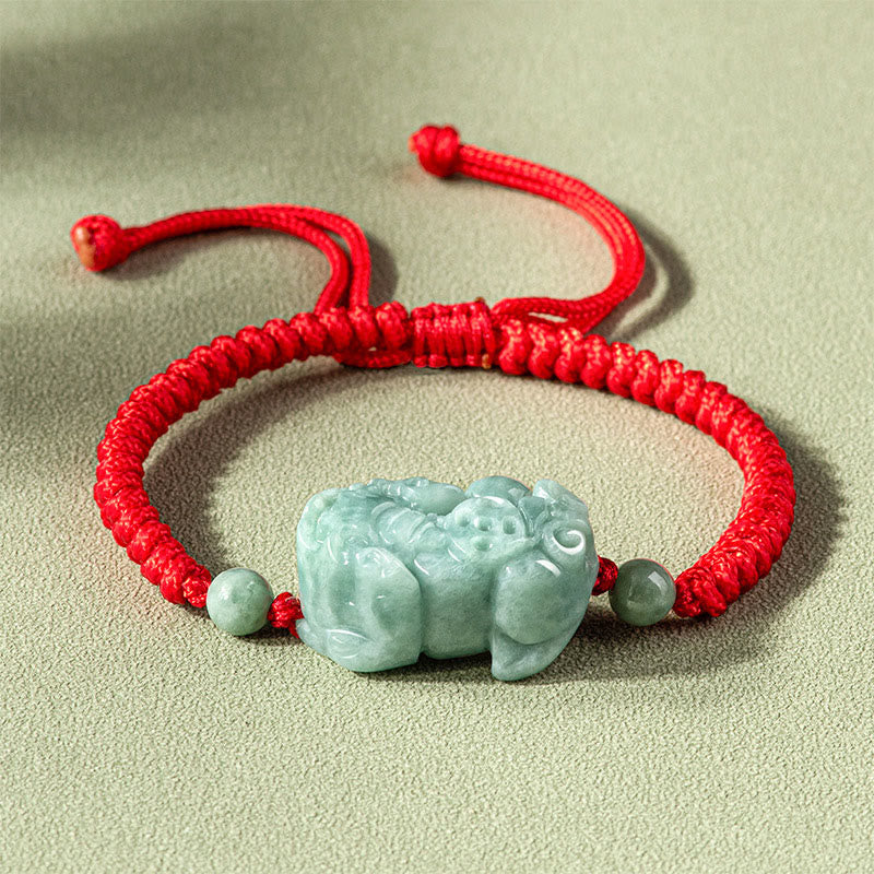 Jade PiXiu Knot Bracelet – Red braided cord bracelet with light green jade PiXiu on beige surface, protection jewelry