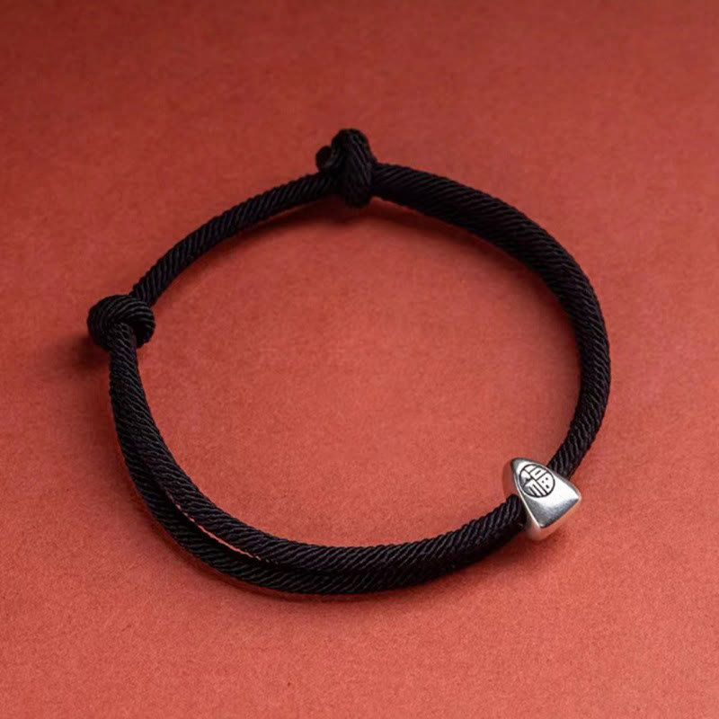 925 Silver Fu Character Braided Bracelet – Black braided cord with silver fortune charm on terracotta orange textured background, overhead flat lay product shot
