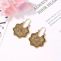 Tibetan Copper Lotus Engraving Drop Earrings – Statement copper mandala earrings featuring elaborate concentric floral patterns with French hooks, displayed on white surface with pink flower accents