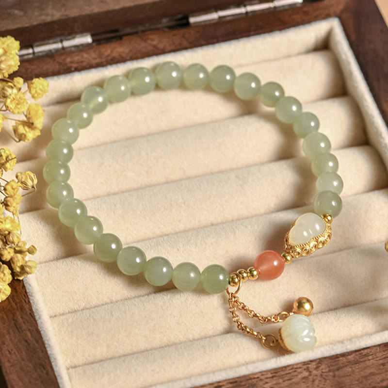 Jade Gourd Lotus Bracelet heart centerpiece macro on gray linen over wood, red backdrop, artisan craft
