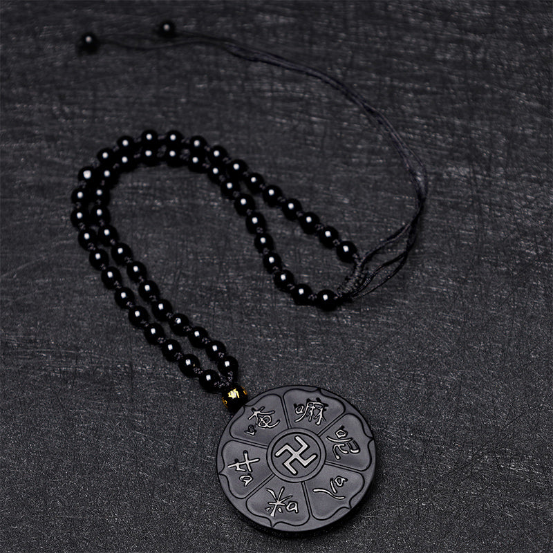 Black Obsidian Swastika Mantra Necklace - Flat lay on dark fabric, full beaded necklace with mantra pendant, meditation accessory
