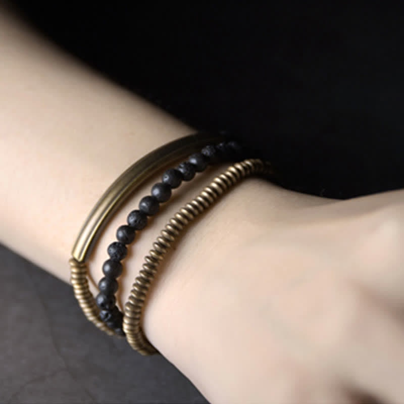 Lava Rock Copper Healing Bracelet – Volcanic black beads with copper wire-wrapped element and silver-toned accents on dark gray stone, three-quarter low angle