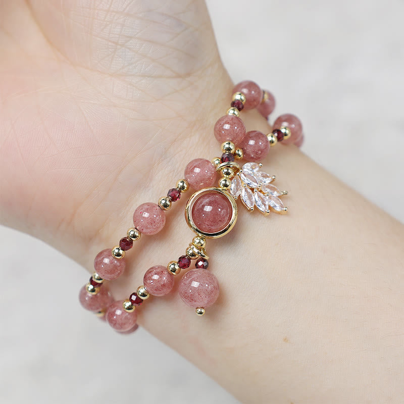 Strawberry quartz double-strand bracelet worn on wrist showing pink beads with natural inclusions garnet red spacers gold findings and delicate crystal leaf charm